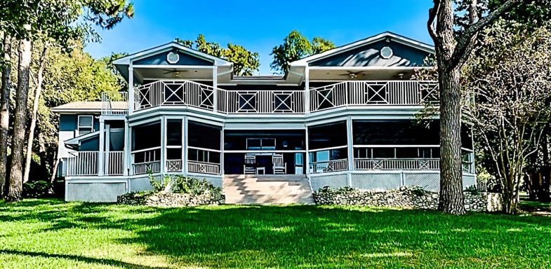 "Elegant Southern-style home with a wraparound porch, inspired by the Hamptons but built in the heart of Texas, featuring custom patio scree